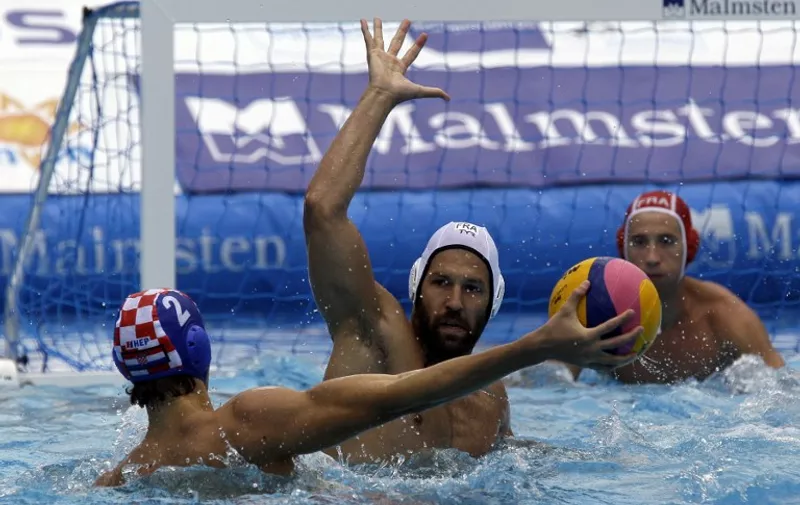 Croatia's Luka Bukic (blue) shots the ball against France's Thibaut Simon (white) during the Water Polo European Championships match for men between their teams in Budapest on July 17, 2014. (at R - French goalkeeper - Remi Garsau)   AFP PHOTO / PETER KOHALMI / AFP / ATTILA KISBENEDEK