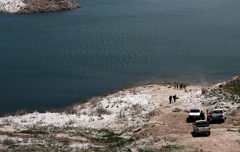 Photo released by Telam of policemen standing on the banks of an artificial lake in the Mendoza river, where a helicopter carrying two members of a team recording for a reality show of US MTV sunk after exploding in Potrerillos, some 30 km southeast of Mendoza, Argentina on December 12, 2015. Both occupants were killed. AFP PHOTO / TELAM / ALFREDO PONCE / AFP / TELAM / ALFREDO PONCE