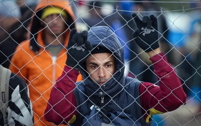 A migrant hangs onto a wire fence at the Greek-Macedonian border near Gevgelija on November 26, 2015 as migrants and refugees attempt to cross the border. Over 200 migrants on November 26 tried to break through barbed wire fences on Greece's border with Macedonia, throwing stones at riot police. At least three migrants tried to get across in the assault as the crowd shouted "Open the border" to the Macedonia police ranged across them. AFP  PHOTO / ROBERT ATANASOVSKI / AFP / ROBERT ATANASOVSKI