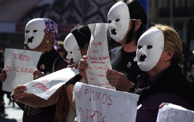 Masked demonstrators hold posters against gender violence during a demonstration against domestic violence in Madrid on November 7, 2015. Forty one women have been murdered in Spain since the start of the year as a a result of domestic violence. AFP PHOTO / CURTO DE LA TORRE