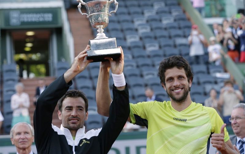 Brazil's Marcelo Melo (R) and Croatia's Ivan Dodig celebrate with the trophy following their victory over US Bob and Mike Bryan celebrate at the end of the men's double final match of the Roland Garros 2015 French Tennis Open in Paris on June 6, 2015.    AFP PHOTO / KENZO TRIBOUILLARD