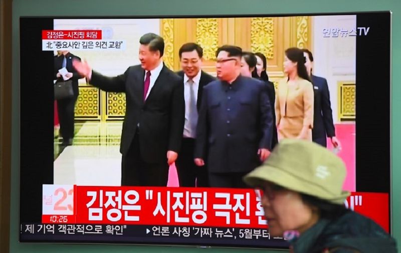 A woman walks past a television news screen reporting about a visit to China by North Korean leader Kim Jong Un, at a railway station in Seoul on March 28, 2018.
North Korea's Kim Jong Un told Chinese President Xi Jinping that it was his "solemn duty" to make Beijing his first overseas destination and invited him to visit Pyongyang, the North's official news agency reported on March 28. / AFP PHOTO / Jung Yeon-je