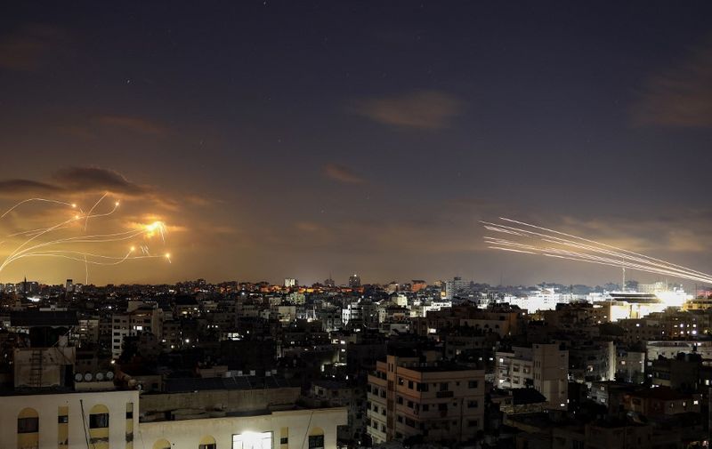 A picture shows rockets fired from the Gaza City (R) being intercepted by Israel's Iron Dome defence missile system (L) on October 10, 2023. Israel said it recaptured Gaza border areas from Hamas as the war's death toll passed 3,000 on October 10, the fourth day of gruelling fighting since the Islamists launched a surprise attack. (Photo by Eyad BABA / AFP)