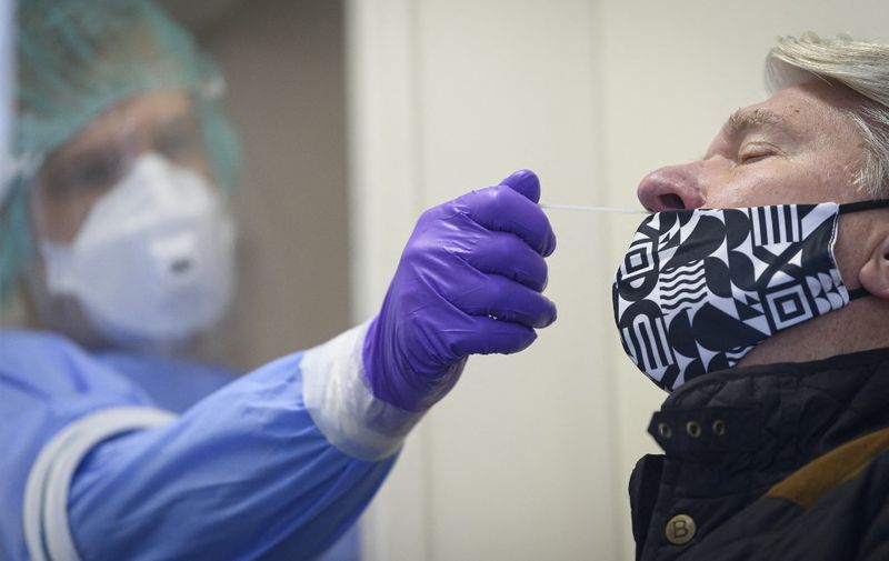 A nurse swabs the nose of a patient as he administers a COVID-19 test in Ljubljana on December 22, 2020, as nation wide mass free rapid testing for the novel coronavirus Covid-19 starts. (Photo by Jure Makovec / AFP)