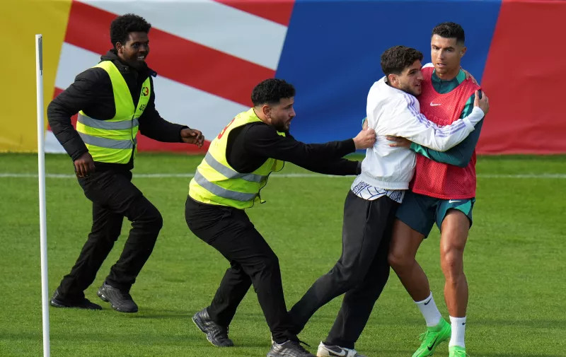 A pitch invader catches Portugal's Cristiano Ronaldo during a training session in Gutersloh, Germany, Friday, June 14, 2024. Portugal will play against Czech Republic during their Group F soccer match at the Euro 2024 soccer tournament on June 18. (AP Photo/Hassan Ammar)