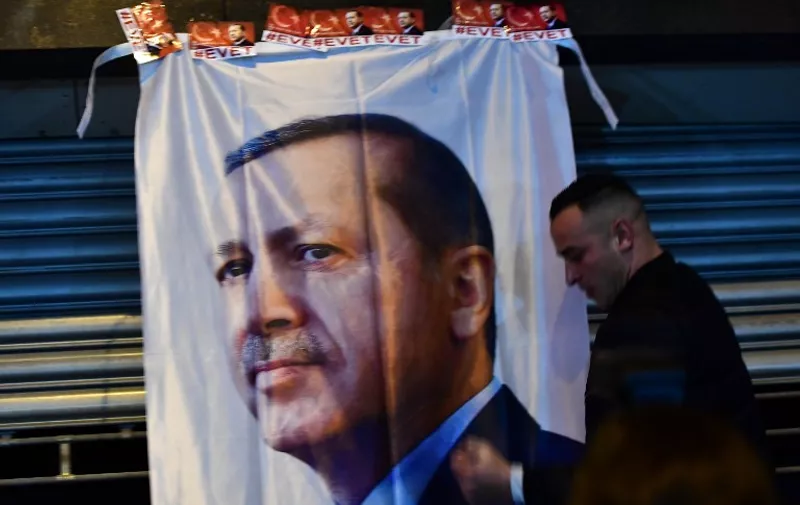 A man gestures in front of a flag bearing a portrait of Turkish President Recep Tayyip Erdogan as Turkish residents of the Netherlands gather for a protest outside Turkey's consulate in Rotterdam on March 11, 2017. 
Protests erupted in the Dutch port city of Rotterdam late on March 11 outside the Turkish consulate amid a row with Ankara after Dutch authorities banned the visits of Turkish ministers. About 1,000 people waving Turkish flags gathered on the street leading to the consulate, as tensions rocketed over rallies abroad to help Ankara gain backing for an April referendum vote.
 / AFP PHOTO / Emmanuel DUNAND
