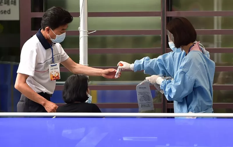 A South Korean medical worker (R) wearing protective gear handles a sample tube from a woman (C) suspected of carrying the MERS virus in front of the emergency section at the Samsung Medical Centre in Seoul on June 8, 2015. South Korea recorded its sixth death and biggest single day jump in Middle East Respiratory Syndrome (MERS) infections on June 8, with 23 new cases in the largest outbreak of the potentially deadly virus outside Saudi Arabia. Among the 23 new cases, 17 were infected at the Samsung Medical Centre in southern Seoul, the health ministry said. AFP PHOTO / JUNG YEON-JE