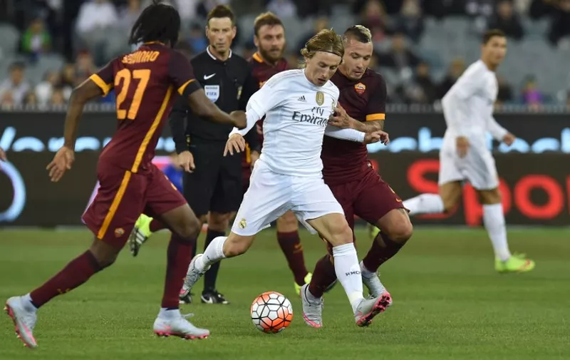 Real Madrid's Luka Modric  (C) fights through the pack during the International Champions Cup football match between Real Madrid and AS Roma in Melbourne on July 18, 2015. AFP PHOTO / Paul CROCK -- IMAGE RESTRICTED TO EDITORIAL USE - STRICTLY NO COMMERCIAL USE