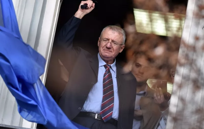 Serb  ultranationalist leader Vojislav Seselj waves at supporters on November 12, 2014 after arriving at his Radical Serb Party (SRS) headquarters in Zemun, near Belgrade . Ailing Serb leader Seselj, who has been released from the UN Yugoslav war crimes tribunal, arrived on November 12 from the Netherlands to Serbia. The International Criminal Tribunal for the former Yugoslavia (ICTY) last week ordered Seselj's release so he could return home for cancer treatment as he awaits a verdict on alleged war crimes during the Balkan wars. Seselj, accused of leading ethnic Serb volunteers in persecuting Croats, Muslims and other non-Serbs during the 1990s wars, underwent colon cancer surgery in December.  AFP PHOTO / ANDREJ ISAKOVIC