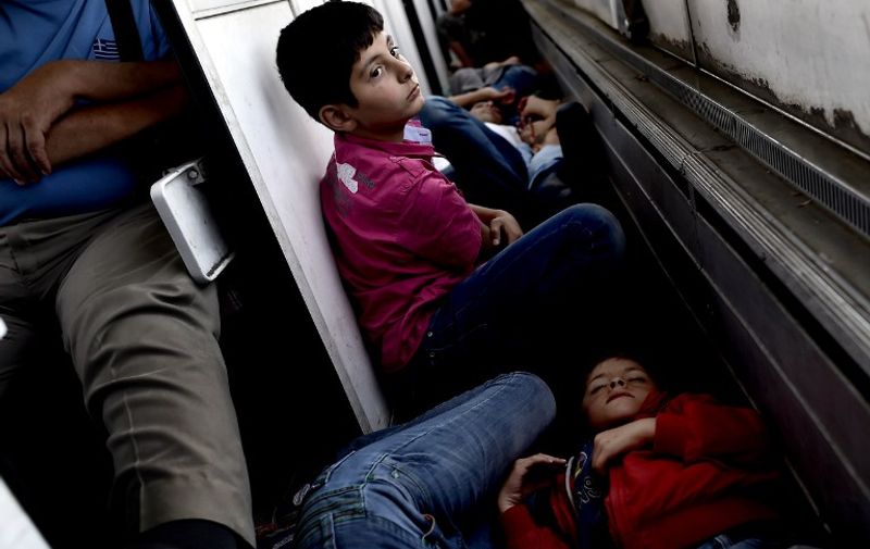 Syrian refugees and migrants travel on a train taking them from Macedonia (Also referred to as the Former Yugoslav Republic of Macedonia) to the Serbian border, on August 30, 2015. The EU is grappling with an unprecedented influx of people fleeing war, repression and poverty in what the bloc has described as its worst refugee crisis in 50 years. AFP PHOTO / ARIS MESSINIS