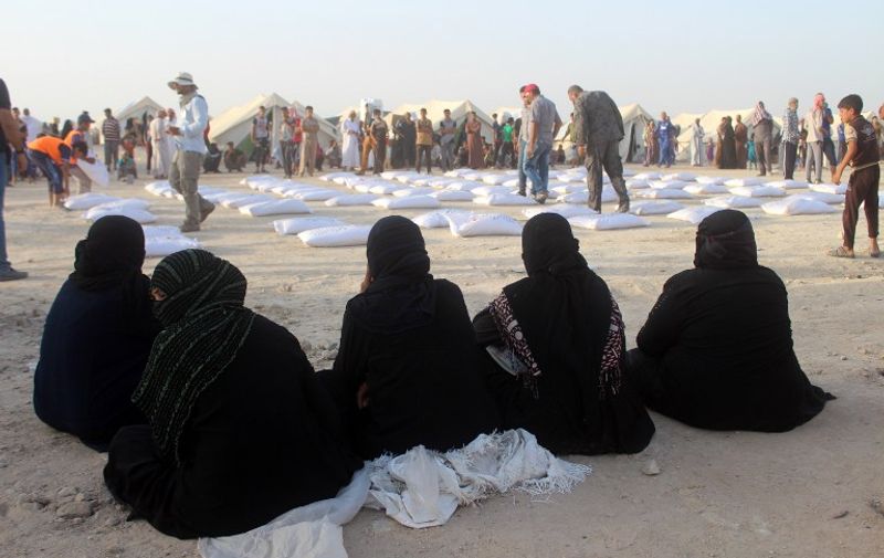 Iraqi women displaced from Ramadi, sit and wait to receive aid from the International Committee of the Red Cross (ICRC) at a makeshift camp where they are taking shelter in Habbaniyah, just east of the capital of Iraq's Anbar province on June 23, 2016. 
Iraqi government forces retook control of the city of Ramadi from the Islamic State (IS) group in February 2016 but sporadic IS attacks there have continued.  / AFP PHOTO / MOADH AL-DULAIMI