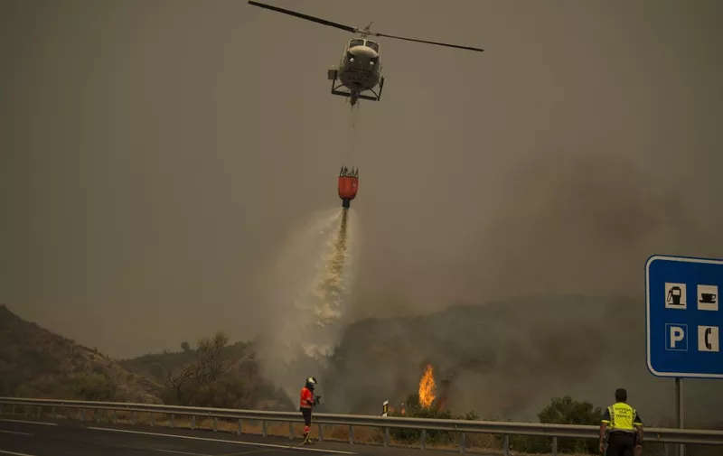 A helicopter drops water over a wildfire in Estepona, Malaga province, on September 9, 2021. - Almost a thousand people had to be evacuated preventively from their homes due to a forest fire in southern Spain, which firefighters continue to fight today, authorities reported. (Photo by JORGE GUERRERO / AFP)