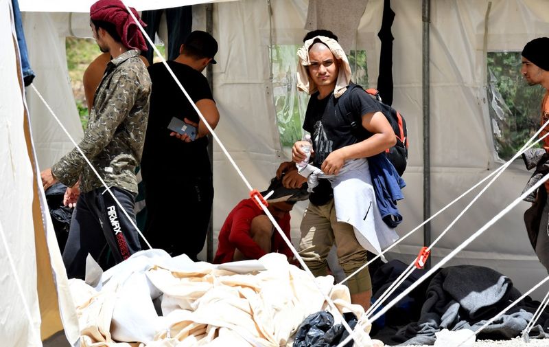 Illegal migrants from Asia and Africa shelter under tents at camp "Vucjak" on the outskirts of the city of Bihac, in northern Bosnia on June 16, 2019. - Local authorities in have started the relocation of illegal migrants and refugees residing in private accommodation in Bihac to camp Vucjak.  In an earlier report, the UN expressed serious concern with regard to this decision, as this location is deemed entirely inadequate for the purpose of accommodating people. (Photo by ELVIS BARUKCIC / AFP)