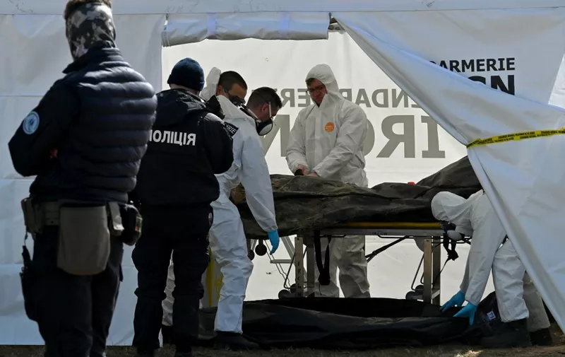 French forensic investigators from Institut de recherche criminelle de la gendarmerie nationale (IRCGN) examine a body in a tent after it was exhumed from a mass grave in the Ukrainian town of Bucha, northwest of Kyiv on April 14, 2022. - French gendarmes and forensic doctors have arrived in Ukraine to help investigate the discovery of scores of bodies in civilian clothing scattered in Bucha and other towns around Kyiv after Russia's withdrawal from the region. Ukraine says it has discovered 1,222 bodies in Bucha and other towns. (Photo by Sergei SUPINSKY / AFP)