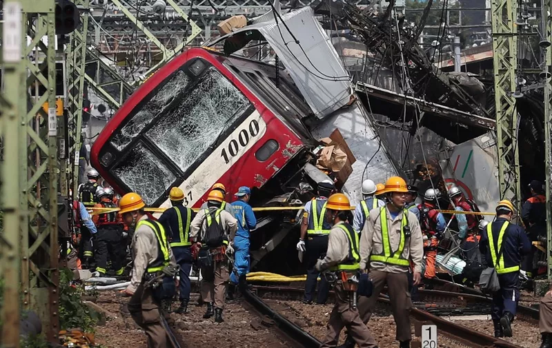 Rescue team work at the crash site, where a train is derailed after a collision with a truck at a crossing in Yokohama, Kanagawa Prefecture on September 5, 2019. (Photo by JIJI PRESS / JIJI PRESS / AFP) / Japan OUT