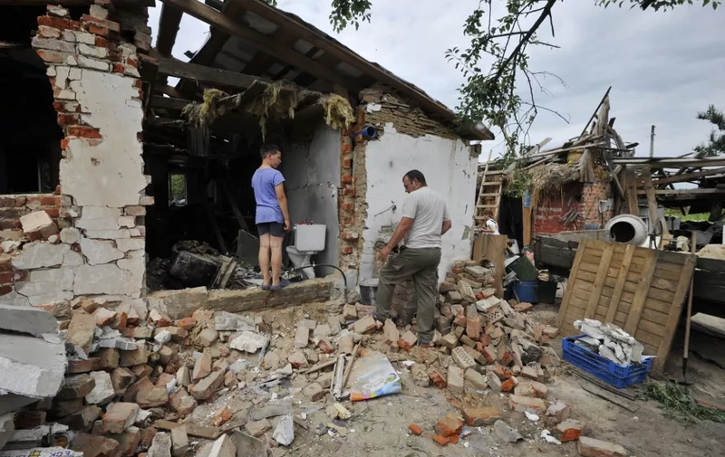 People clear debris of a house, destroyed during Russia's invasion of Ukraine in the village of Pidgayne, Kyiv region, on July 9, 2022. (Photo by Sergei CHUZAVKOV / AFP)