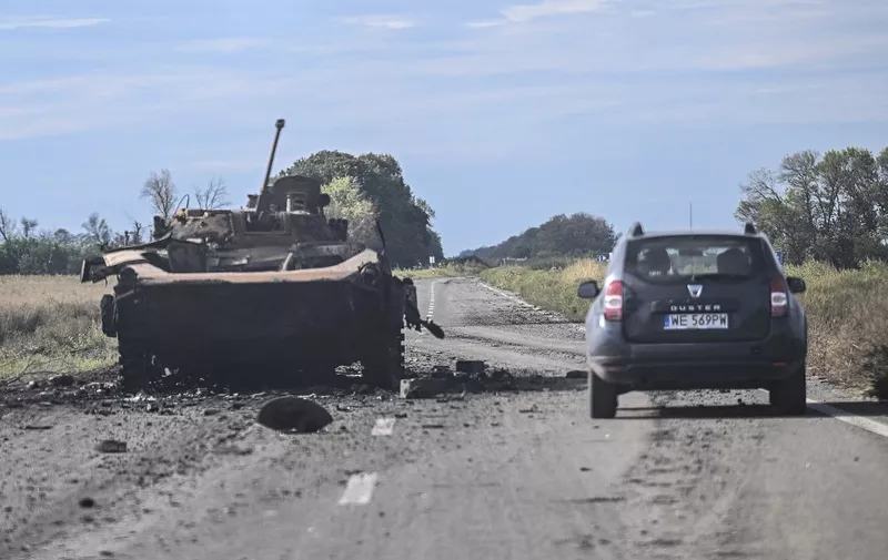 A car drives past a destroyed armored vehicle in Balakliya, Kharkiv region, on September 10, 2022, amid the Russian invasion of Ukraine. - Ukrainian forces said on September 10, 2022 they had entered the town of Kupiansk in eastern Ukraine, dislodging Russian troops from a key logistics hub in a lightning counter-offensive that has seen swathes of territory recaptured. (Photo by Juan BARRETO / AFP)