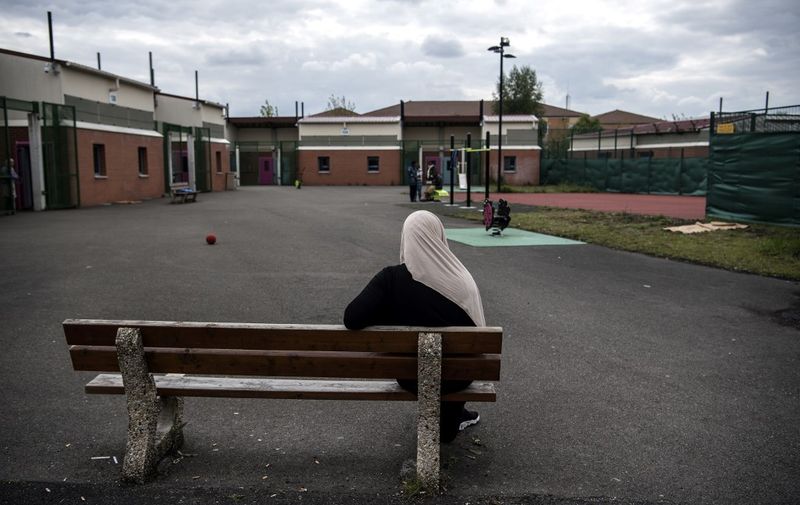 A woman sits on a bench in a courtyard of the Administrative Detention Centre (Centre de Retention Administrative - CRA) in Le Mesnil-Amelot, north of Paris, on May 6, 2019. (Photo by Christophe ARCHAMBAULT / AFP)