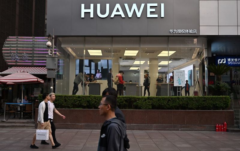 People walk past a Huawei store in Shanghai on May 10, 2019. (Photo by HECTOR RETAMAL / AFP)