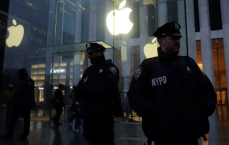 Two New York Police Department (NYPD) officers stand gaurd during a demonstration outside the Apple store on Fifth Avenue in New York on February 23, 2016. - Apple is battling the US government over unlocking devices in at least 10 cases in addition to its high-profile dispute involving the iPhone of one of the San Bernardino attackers, court documents show. Apple has been locked in a legal and public relations battle with the US government in the California case, where the FBI is seeking technical assistance in hacking the iPhone of Syed Farook, a US citizen, who with his Pakistani wife Tashfeen Malik in December gunned down 14 people. (Photo by Jewel Samad / AFP)