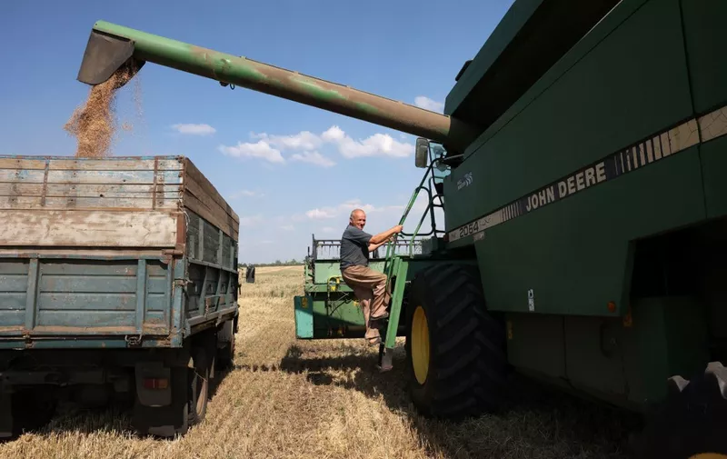 A combine operator climbs aboard a combine as they harvest wheat at a farm near Kramatorsk, in Donetsk region on August 4, 2023, amid the Russian invasion of Ukraine. Known as the world's "bread basket", Ukraine grows far more wheat than it consumes and it's exports contribute to global food security, especially in African countries, which now fear food shortages. Russia announced on July 17, 2023 it's withdrawal from the so-called Black Sea grain agreement allowing safe passage for grain cargo ships from Ukrainian Black Sea ports, leading to a spike in grain prices that has hit poorer countries hard. (Photo by Anatolii Stepanov / AFP)