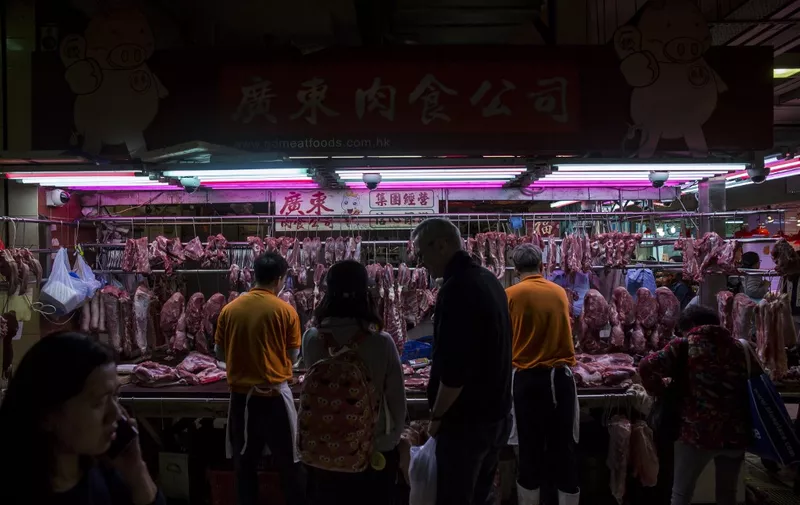 Customers (C) purchase pork from a stall at the Wan Chai wet market in Hong Kong on January 5, 2019. (Photo by ISAAC LAWRENCE / AFP)