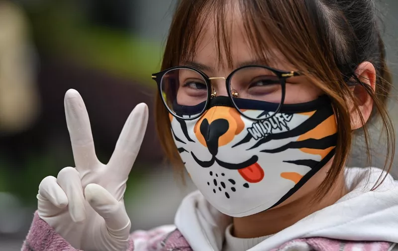 A woman wearing a face mask gestures on a street in Wuhan, China's central Hubei province on April 3, 2020. - Wuhan, the central Chinese city where the coronavirus first emerged last year, partly reopened on March 28 after more than two months of near total isolation for its population of 11 million. (Photo by Hector RETAMAL / AFP)