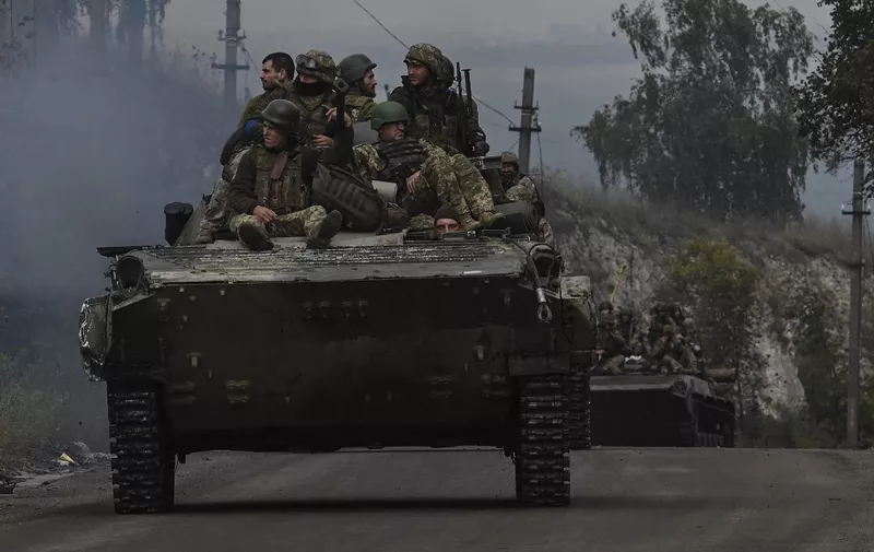 Ukrainian soldiers sit on infantry fighting vehicles as they drive near Izyum, eastern Ukraine on September 16, 2022, amid the Russian invasion of Ukraine. (Photo by Juan BARRETO / AFP)