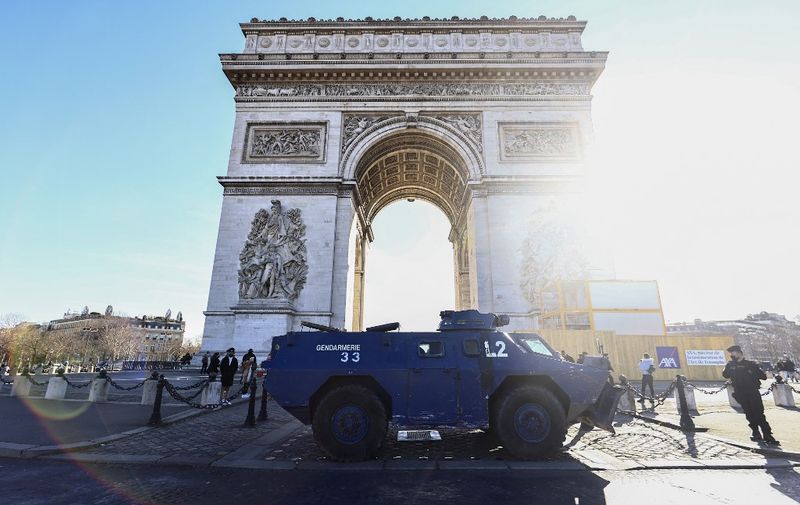 French gendarmes stand next to an armored vehicle VBRG parked at the Arc de Triomphe, in Paris, on February 12, 2022, as convoys of protesters from the "Convoi des Libertes" arrive in the French capital. - Thousands of protesters in convoys, inspired by Canadian truckers paralysing border traffic with the US, were heading to Paris from across France on February 11, with some hoping to blockade the capital in opposition to Covid-19 restrictions despite police warnings to back off. The protesters include many anti-Covid vaccination activists, but also people protesting against fast-rising energy prices that they say are making it impossible for low-income families to make ends meet. (Photo by Sameer Al-DOUMY / AFP)