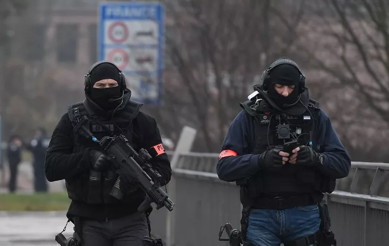 Two members of the French police unit BRI (Research and Intervention Brigade - Brigades de recherche et d'intervention) walk on the Pont de l'Europe (Europe bridge), crossing the border with Germany over the river Rhine in Strasbourg, on December 12, 2018, as part of searches in order to find the gunman who opened fire near a Christmas market the night before, in Strasbourg, eastern France. Hundreds of security forces were deployed in the hunt for a lone gunman who killed at least two people and wounded a dozen others at the famed Christmas market in Strasbourg, with the French government raising the security alert level and reinforcing border controls. (Photo by Frederick FLORIN / AFP)
