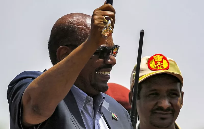 In this picture taken on September 23, 2017, Sudanese President Omar al-Bashir (L) waves a walking stick as he gives a speech at the headquarters of the Rapid Support Forces (RSF) paramilitaries in Umm al-Qura in South Darfur State, while accompanied by RSF commander Mohamed Hamdan Daglo. (Photo by ASHRAF SHAZLY / AFP)