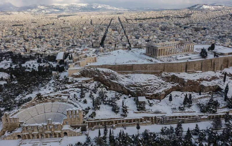 The snow covered Ancient Temple of Parthenon atop the Acropolis hill is pictured on January 25, 2022, after a heavy snowfall in Athens. (Photo by ARIS MESSINIS / AFP)