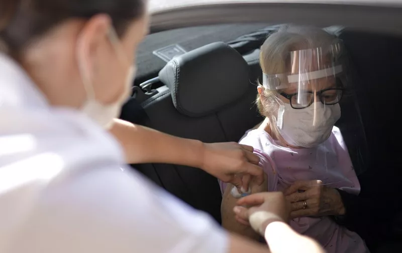 Military personnel of the Brazilian Army vaccinate elderly over 89 years of age, with the second dose of the AstraZeneca/Oxford vaccine against the novel coronavirus, COVID-19, at a drive-through vaccination centre in Belo Horizonte, State of Minas Gerais, Brazil, on May 1, 2021. (Photo by Douglas MAGNO / AFP)