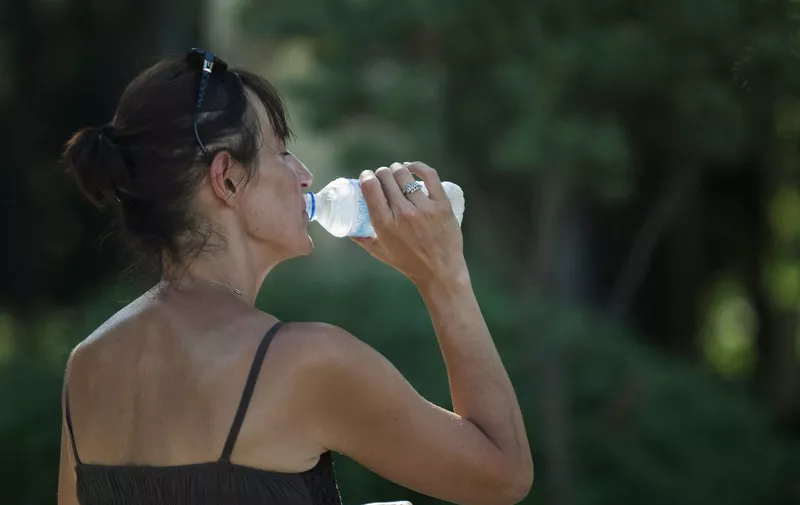 A woman drinks water to cool-off, in Sevilla, on June 14, 2014. Spain's State Meteorological Agency has issued an orange heat alert for provinces today, including Cordoba and Sevilla, with temperatures expected to reach around the 40 degrees Celsius (104 degrees Fahrenheit), according to the agency's website. AFP PHOTO / GOGO LOBATO (Photo by GOGO LOBATO / AFP)
