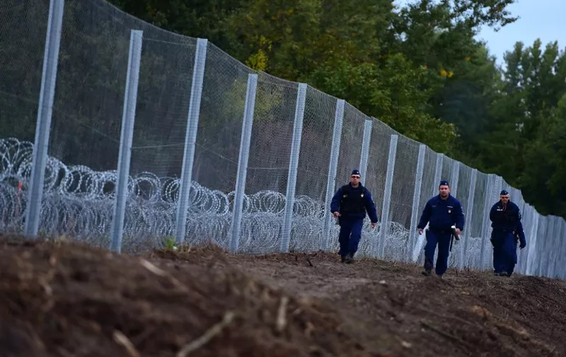 Police officers patrol along a new border fence at the Hungarian-Croatian border near Zakany on October 17, 2015. The border between Hungary and Croatia has been closed to "illegal" migrants, the Hungarian government said, with barbed wire fences being set up to seal the frontier. Croatia announced that it would divert migrants to Slovenia after Hungary said it would close the border with its fellow EU member -- a major transit point for tens of thousands of refugees. AFP PHOTO / ATTILA KISBENEDEK
