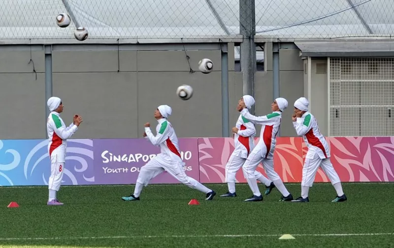 Iranian female football players warm-up before their opening match against Turkey in the Womens' Youth Olympic Football Tournaments 2010 in Singapore on August 12, 2010.   AFP PHOTO/ROSLAN RAHMAN