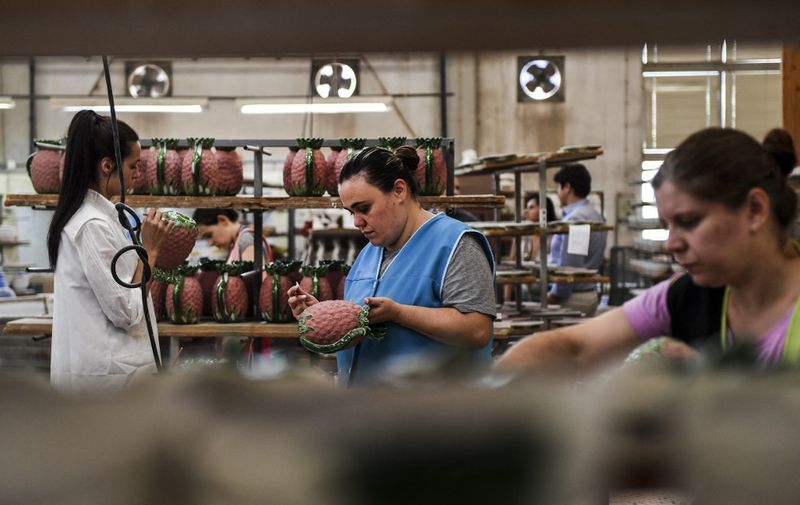 Workers paint ceramic pieces depicting pineapples at Bordallo Pinheiro Factory in Caldas da Rainha on September 13, 2018. - Ignoring temporary walls which point to ongoing large-scale expansion, workers burn the midnight oil at Portugal's byword for ceramic creativity to meet orders from around the globe. For well over a century, the Bordallo Pinheiro site has been producing all manner of artistic glazed pottery designs, and business is booming again a decade after it almost went to the wall. (Photo by PATRICIA DE MELO MOREIRA / AFP)