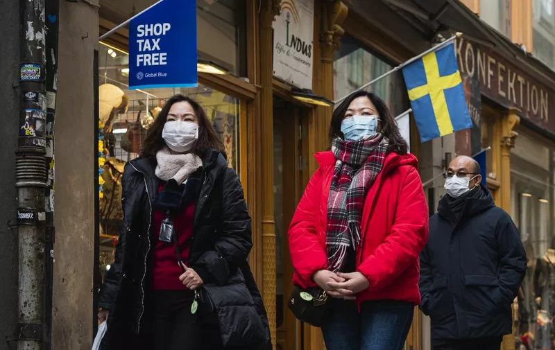 Toursits wear protective face masks due to the new coronanvirus COVID-19 as they visit the old town in Stockholm on March 13, 2020. (Photo by Jonathan NACKSTRAND / AFP)