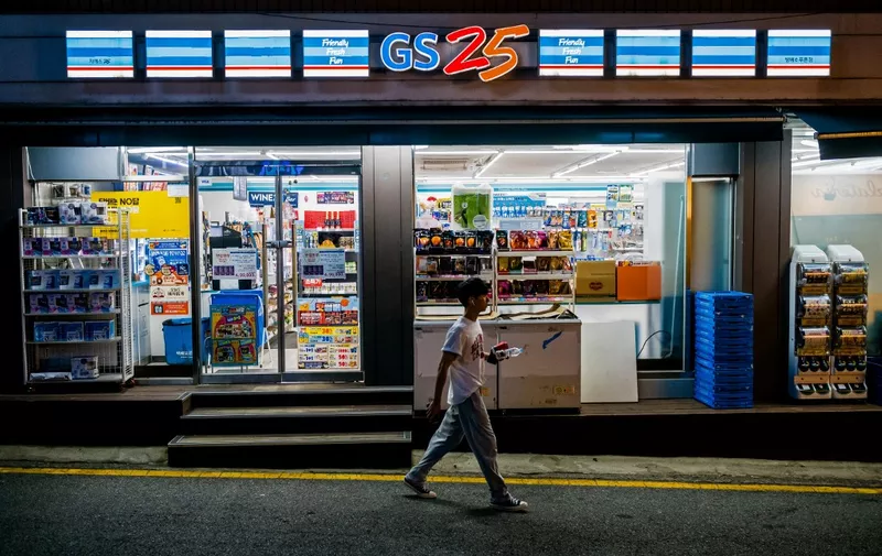 A man walks past a GS25 convenience store along a street in Seoul on August 18, 2023. (Photo by Anthony WALLACE / AFP)