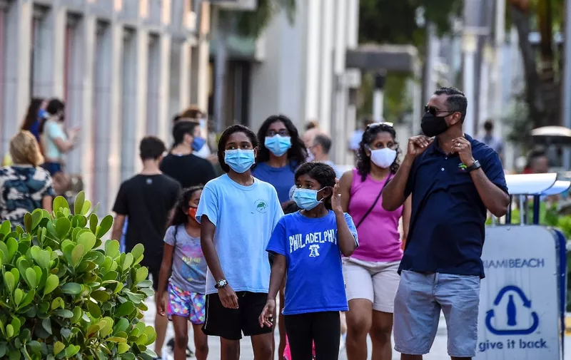 A family wearing facemasks walks at a shopping centre in Miami Beach, Florida on June 29, 2020. - The City of Miami issued an emergency order mandating facial coverings be worn in public at all times and until further notice. Officials will start issuing fines of up to $500 for not wearing a mask in public. (Photo by CHANDAN KHANNA / AFP)
