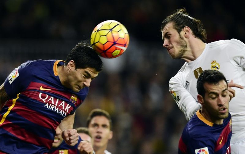 Barcelona's Uruguayan forward Luis Suarez heads the ball next to Real Madrid's Welsh forward Gareth Bale (R top) and teammate Barcelona's midfielder Sergio Busquets (R bottom) during the Spanish league "Clasico" football match Real Madrid CF vs FC Barcelona at the Santiago Bernabeu stadium in Madrid on November 21, 2015. AFP PHOTO/ JAVIER SORIANO / AFP / JAVIER SORIANO
