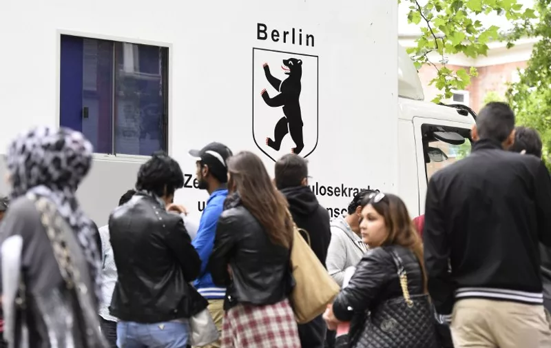 Refugees queue up in front of a medical truck in the yard of the "State Office of Health and Social Affairs" in Berlin's Moabit district on July 31, 2015. Since the start of the year, the total number of asylum-seekers -- not just from war-torn Syria, but also from Kosovo, Albania and other countries -- taken in by Germany is close to 180,000. AFP PHOTO / TOBIAS SCHWARZ