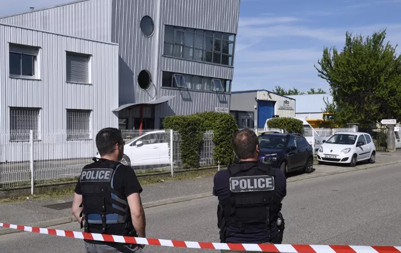 French police officers stand guard near a cordon outside the ATC-Colicom delivery service company in Chassieu near Lyon on June 26, 2015, where the victim who was decapitated during the attack earlier in the day in Saint-Quentin-Fallavier worked. At least one suspected Islamist launched a daylight raid on an industrial gas factory in France and pinned a severed head to the gates, in what President Francois Hollande called a "terrorist" attack. The head of the victim, who ran a delivery service, was found pinned to the gates at the American-owned Air Products factory. AFP PHOTO / PHILIPPE DESMAZES