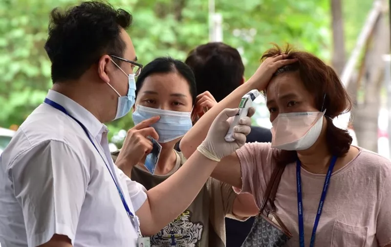 A hospital worker (L) checks the body heat of visitors at a gate of Samsung Medical Center in southern Seoul on July 20, 2015. The hospital at the epicentre of South Korea's deadly MERS outbreak started to resume normal operations on July 20, as officials moved closer to declaring a formal end to a crisis that triggered widespread panic and choked the local economy. AFP PHOTO / JUNG YEON-JE