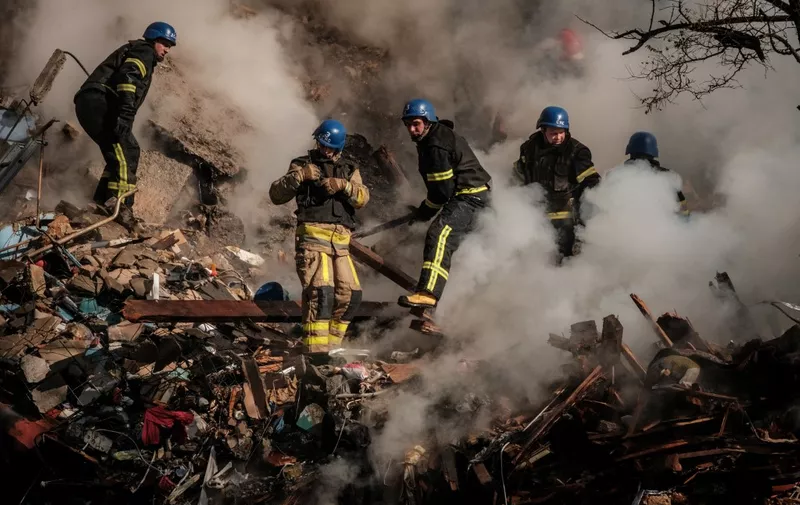 Ukrainian firefighters works on a destroyed building after a drone attack in Kyiv on October 17, 2022, amid the Russian invasion of Ukraine. - Ukraine officials said on October 17, 2022 that the capital Kyiv had been struck four times in an early morning Russian attack with Iranian drones that damaged a residential building and targeted the central train station. (Photo by Yasuyoshi CHIBA / AFP)