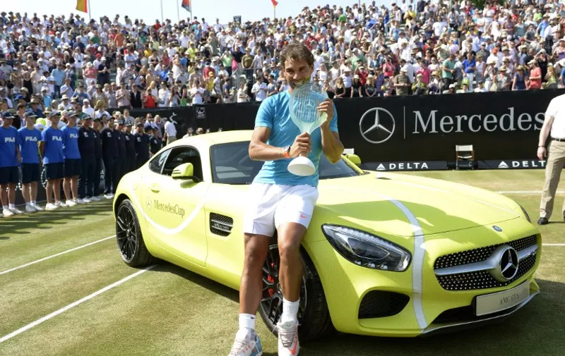 Spain's Rafael Nadal poses on the winner's car, a Mercedes AMG GT S, with the trophy after defeating Serbia's Viktor Troicki in the final match at the ATP Mercedes Cup tennis tournament in Stuttgart, southern Germany, on June 14, 2015.  Rafael Nadal earned his second title of the season and his fourth on grass as he defeated Serb Viktor Troicki 7-6 (7/3), 6-3 to become the first man to triumph on both clay and turf at the Stuttgart Open.   AFP PHOTO / THOMAS KIENZLE