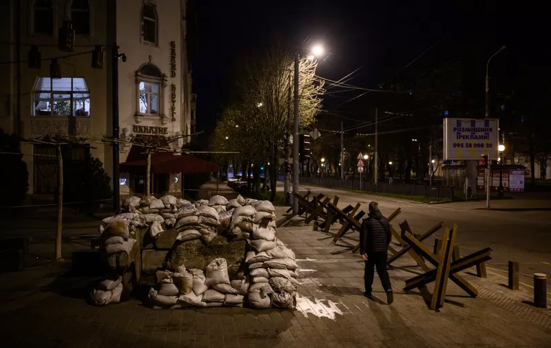 A pedestrian walks along a street past anti-tank obstacles shortly before a curfew in Dnipro on April 14, 2022, amid Russia's military invasion launched on Ukraine. (Photo by Ed JONES / AFP)