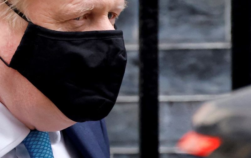 Britain's Prime Minister Boris Johnson, wearing a face covering to help mitigate the spread of coronavirus, leaves from 10 Downing Street in central London on January 26, 2022, to take part in the weekly session of Prime Minister Questions (PMQs) at the House of Commons. - British Prime Minister Boris Johnson braced Wednesday for a potentially damning report into lockdown-breaching parties, after the launch of a police inquiry dramatically upped the stakes. (Photo by Tolga Akmen / AFP)