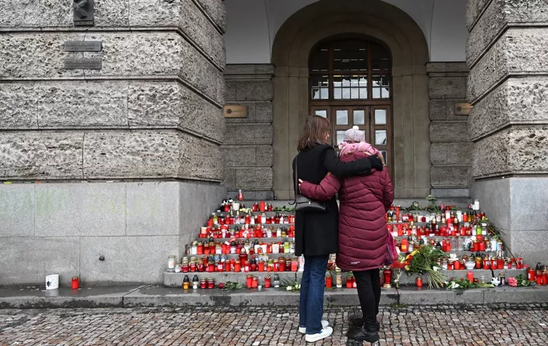 People look at candles placed on the stairs of the building of the Philosophical Faculty of the Charles University in central Prague, on December 24, 2023. A 24-year-old student opened fire at the Faculty of Arts on December 21, 2023, killing 13 people and then himself. Another person died in hospital later on. (Photo by Michal Cizek / AFP)