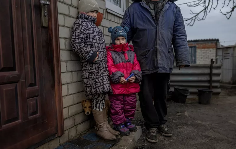 Ukranian children and their father stand at their garden at the eastern Ukrainian village of Zarichne, near the frontline in Donbas region, on November 10, 2022, amid the Russian invasion of Ukraine. - In Zarichne village, which is taken back from the Russian forces few weeks ago, people live without electricity, water and basic needs. (Photo by BULENT KILIC / AFP)